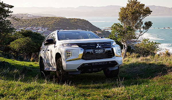 A white suv drivin up a hill toward the veiwing off road